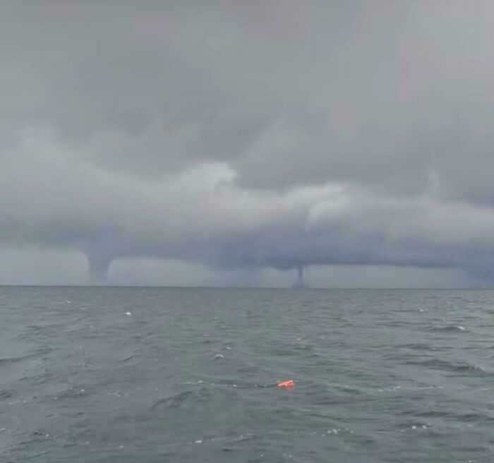 Stormy ocean with two waterspouts under dark clouds, showcasing terrifying nature.