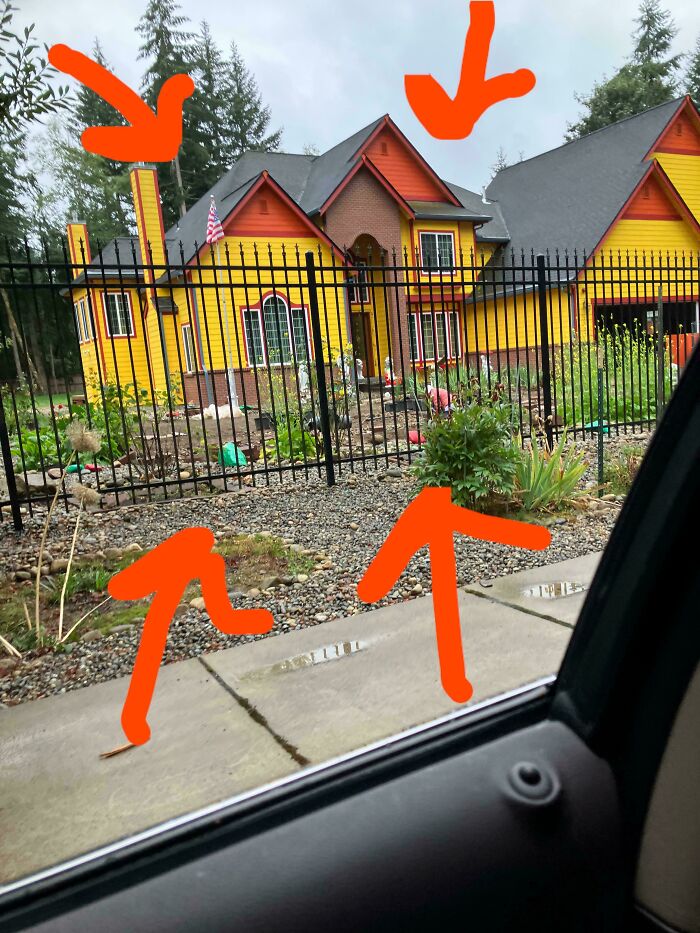 Brightly painted house with mismatched colors, surrounded by a black fence, showcasing that money can't buy taste.