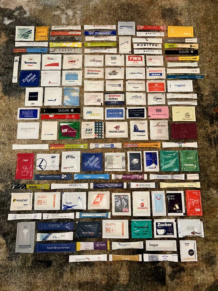 Unique sugar packet collection from various airlines displayed on a textured surface.