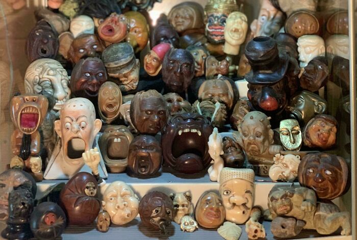 Unique collections of expressive carved faces displayed in a showcase.