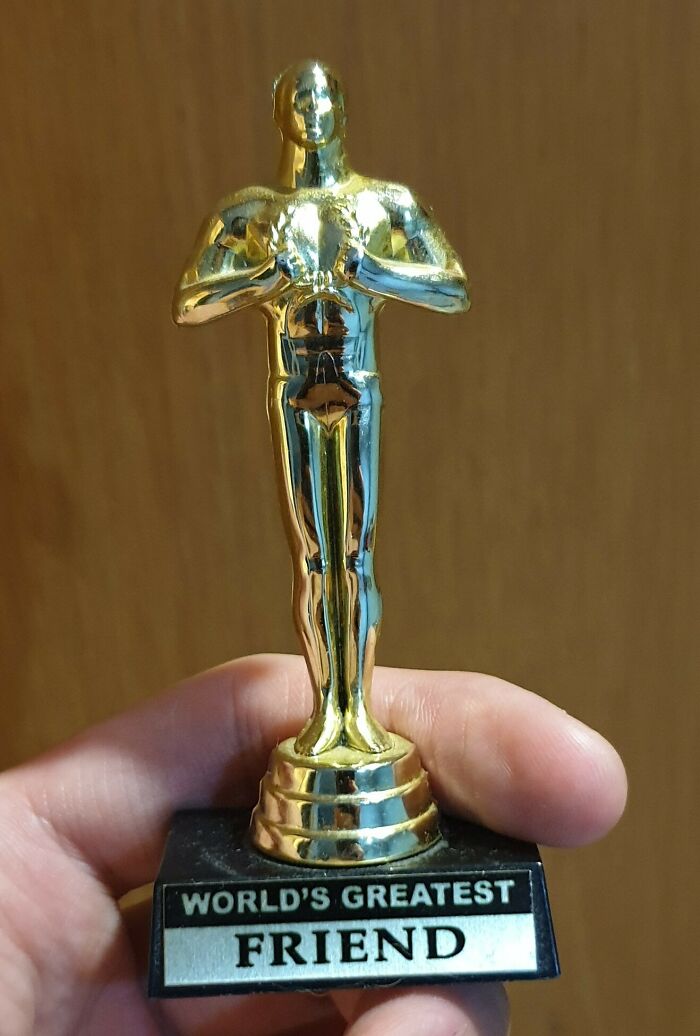 Small golden trophy labeled "World's Greatest Friend," representing a disappointing gift.