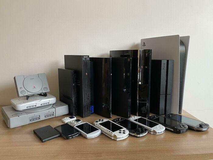 A display of PlayStation consoles showcases an unexpected unique collection on a wooden table.