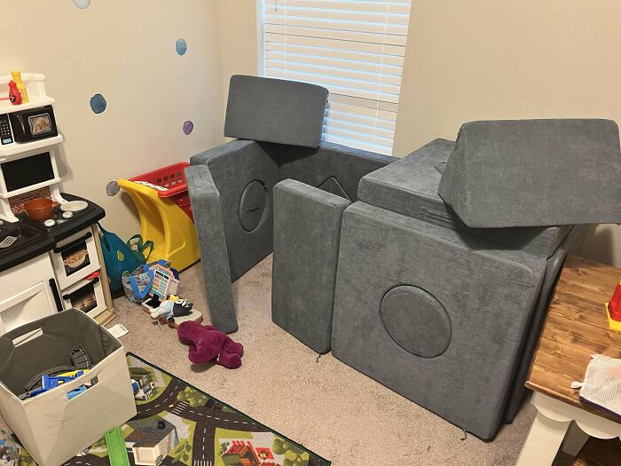 Creative parenting trick using couch cushions to build a fortress in a playroom.