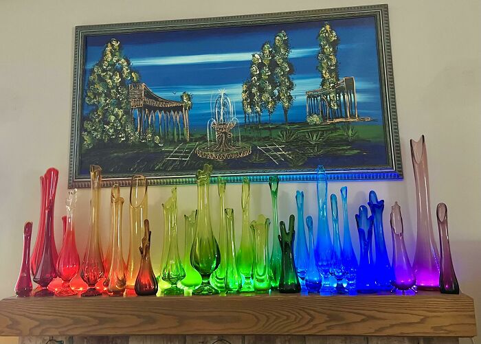 Unique glass collection in rainbow colors displayed under a framed landscape painting.