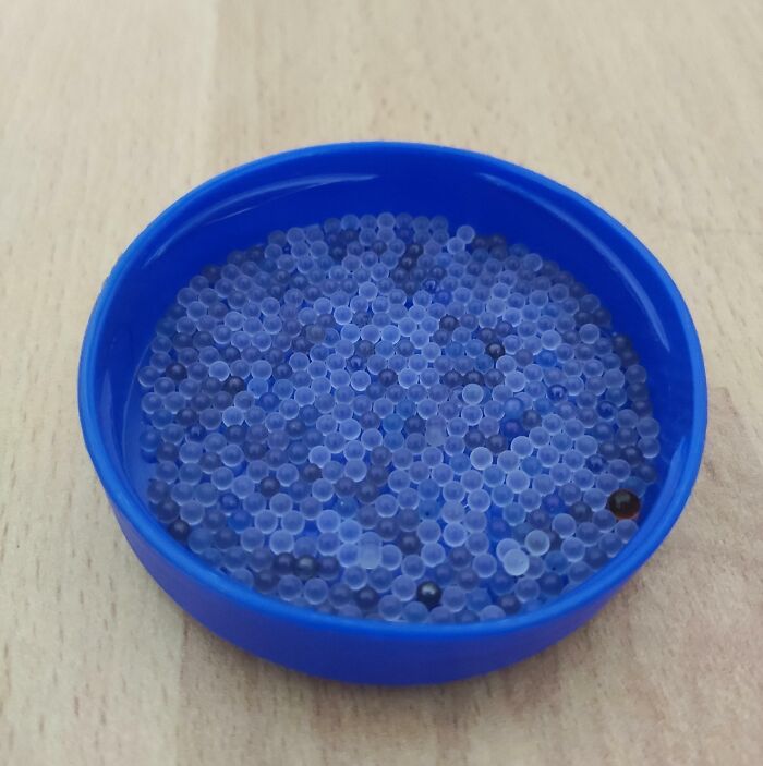 Blue silica gel beads in a round container showcasing unexpected unique collections.