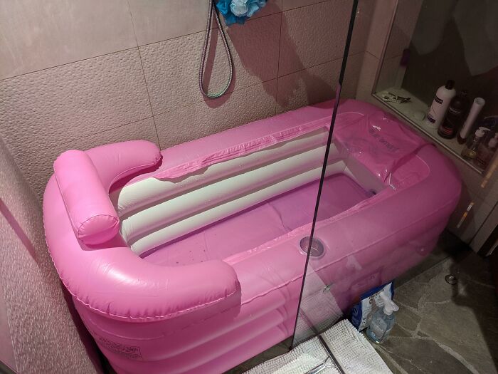 Inflatable pink bathtub inside a shower, highlighting funny pregnancy situations.