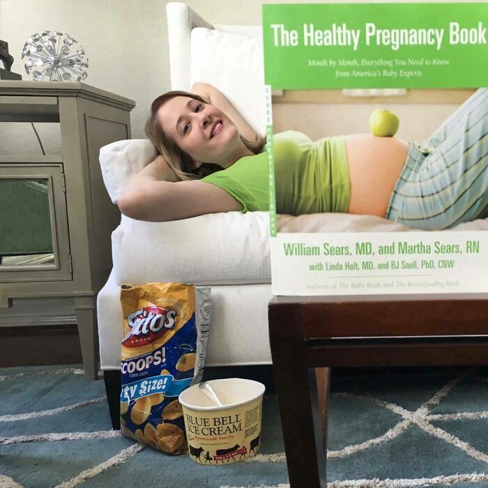 Pregnant woman lounging with snacks and a funny book, showcasing humorous pregnancy situations.