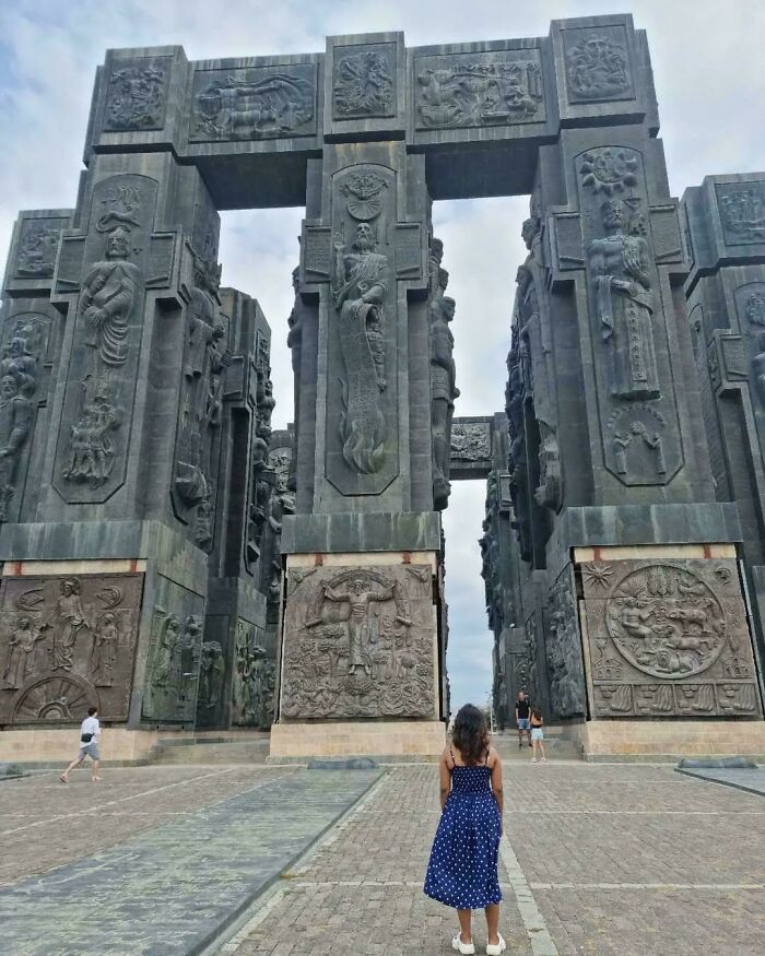 Large ancient stone monument with detailed carvings towering over people, illustrating megalophobia scale in architecture.