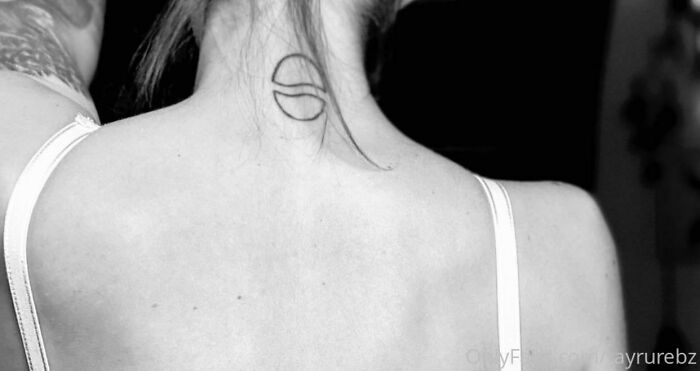Back view of a person with a minimalist tattoo fail on the neck, showcasing a simple black line design.