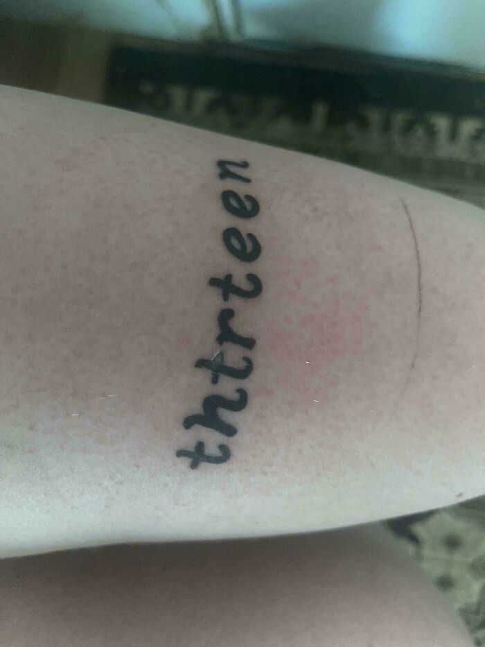 Tattoo fail with misspelled word "thirteen" inked on skin, showcasing a funny mistake.