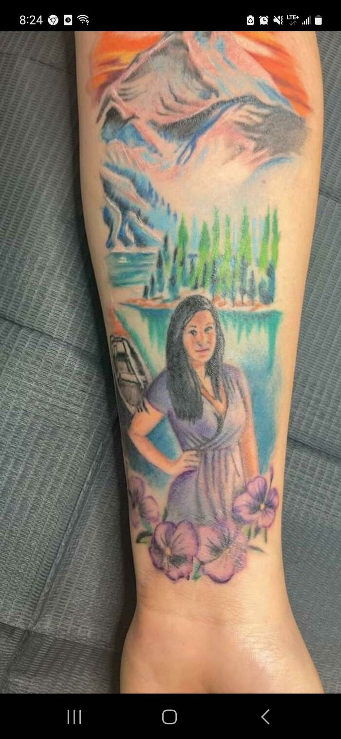 Colorful tattoo with landscape scene and portrait, showcasing a funny worst tattoo fail.