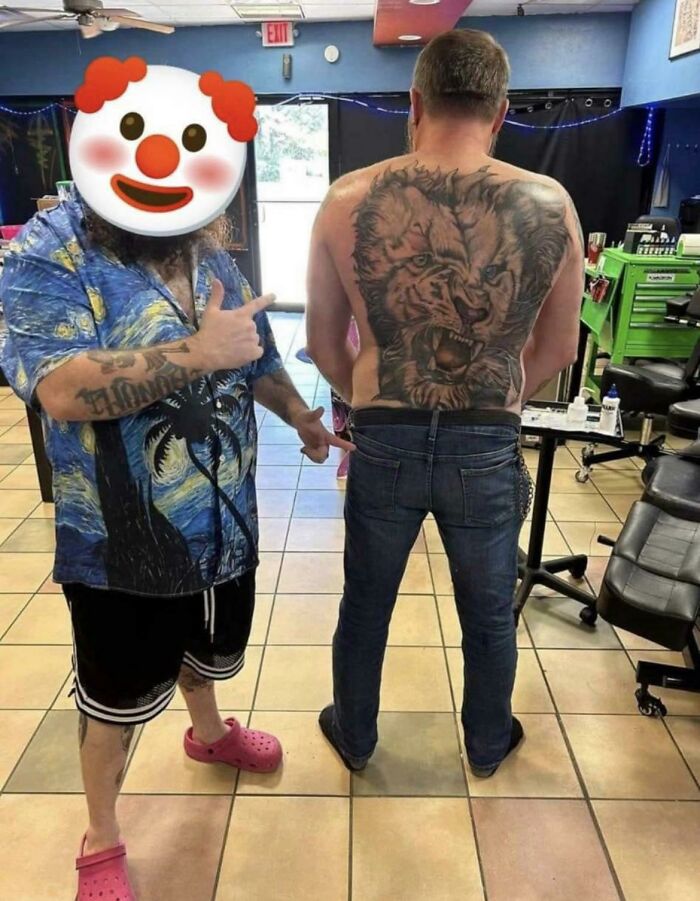 Man in tattoo shop with funny worst tattoo fail of a lion on his back, artist pointing at it.