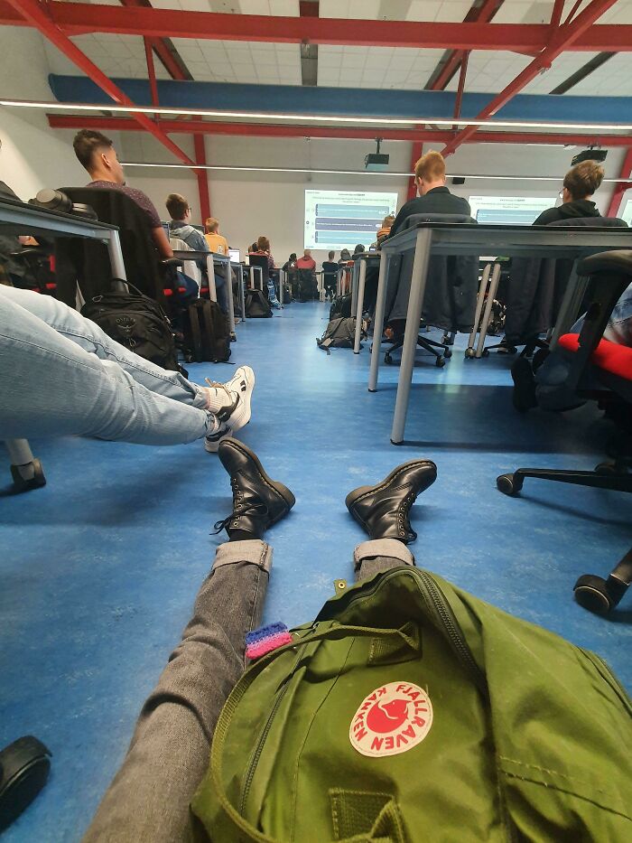 Student lying on the floor in a classroom, surrounded by desks and chairs, depicting a distressing school experience.