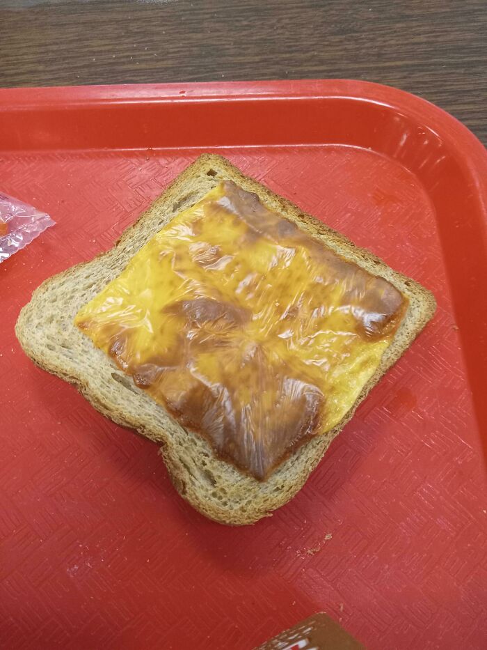 Burnt cheese sandwich on a red tray, depicting horrifying school lunch experience.