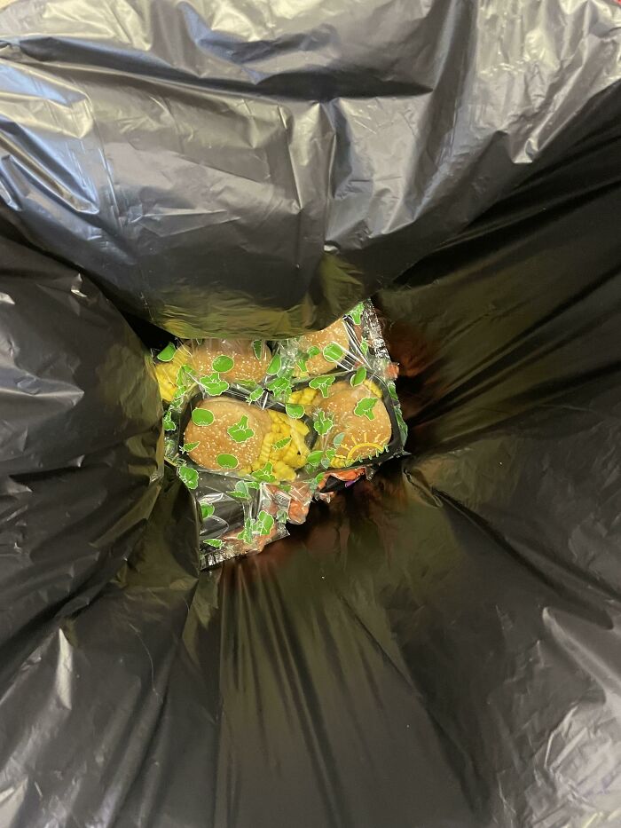 Packaged burgers discarded in a trash bag, reflecting unsettling school experiences.