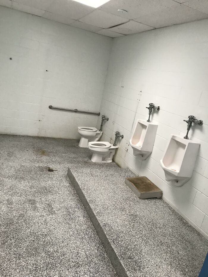 School restroom with an unusual layout featuring two toilets and urinals in one space, reflecting horrifying experiences.