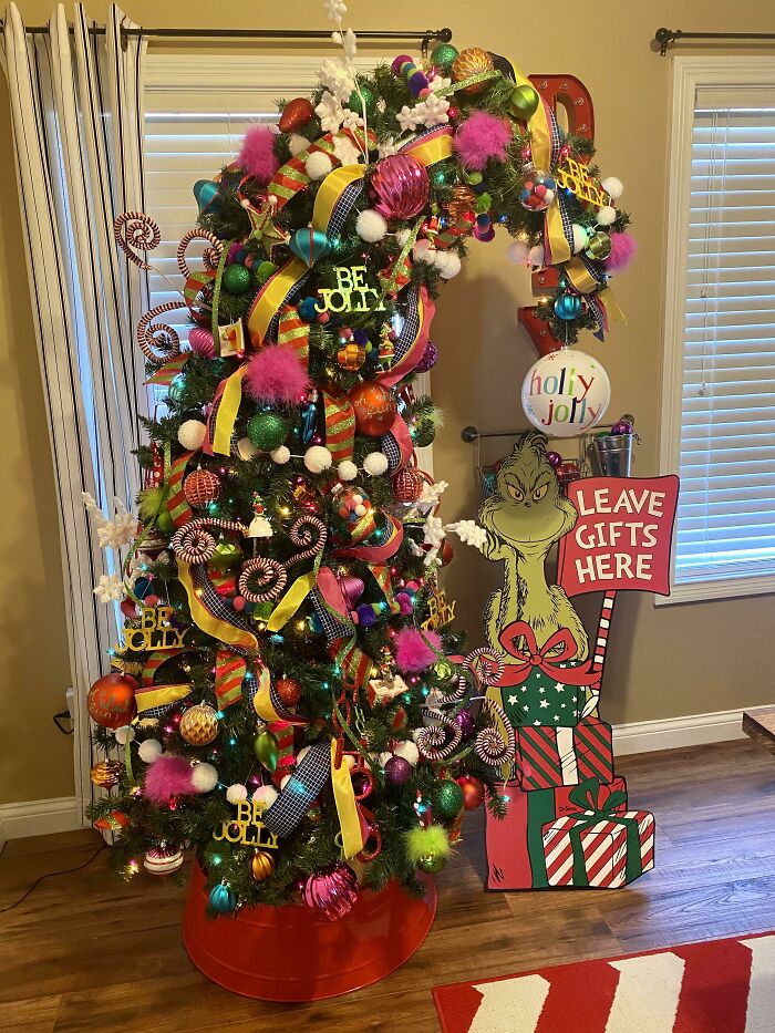 Colorful Christmas tree decorated with ribbons, ornaments, and Grinch cutout.