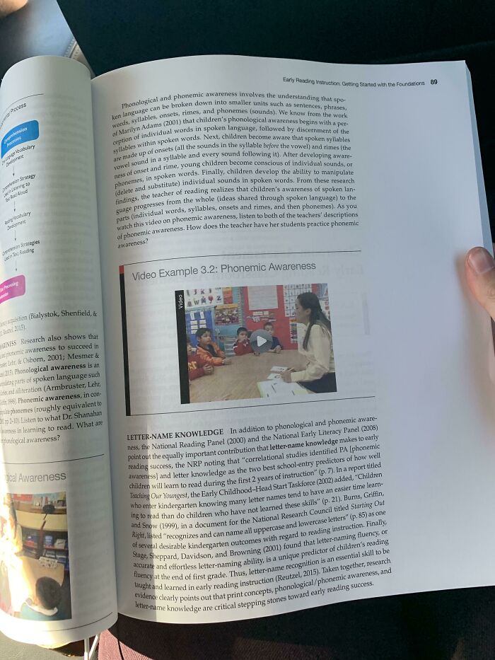 Open book with text on phonemic awareness in US schools, featuring a classroom video example.