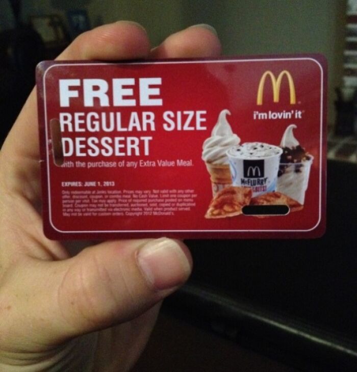 Hand holding a McDonald's free dessert card, related to horrifying school experiences.