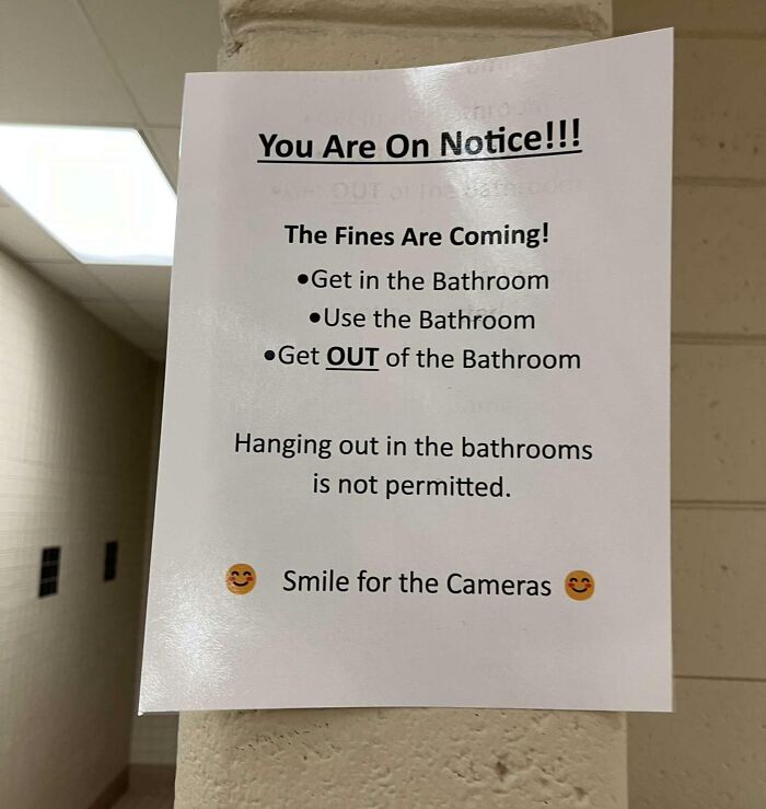 Notice on school bathroom wall about usage rules, highlighting fines and surveillance.