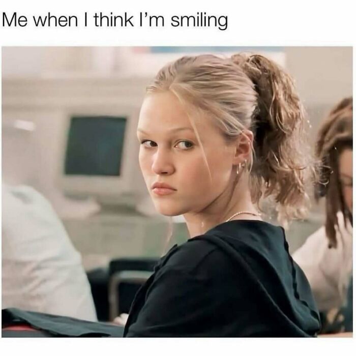 Woman looking serious with text "Me when I think I'm smiling," capturing humor and relatability through memes.