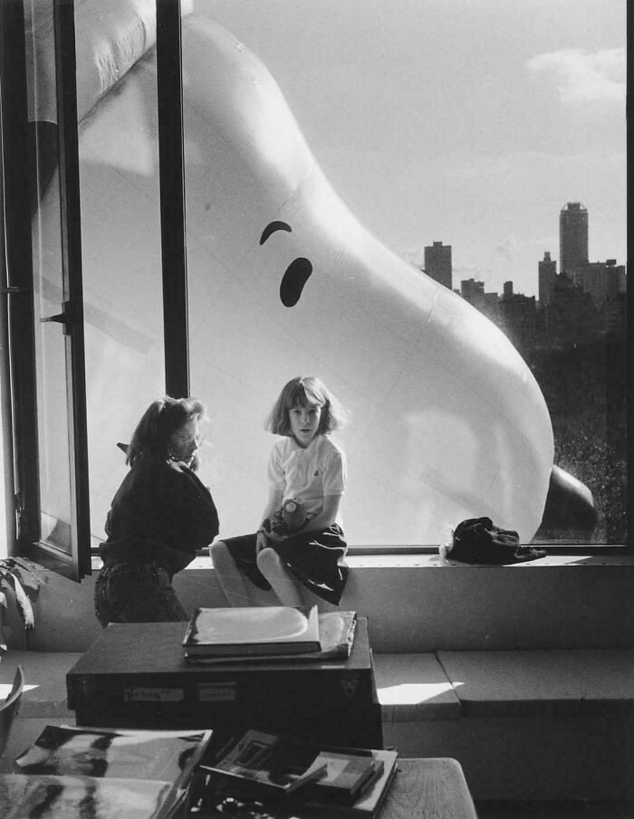 Two children inside a room with a giant inflatable outside the window, providing a new perspective on famous events.
