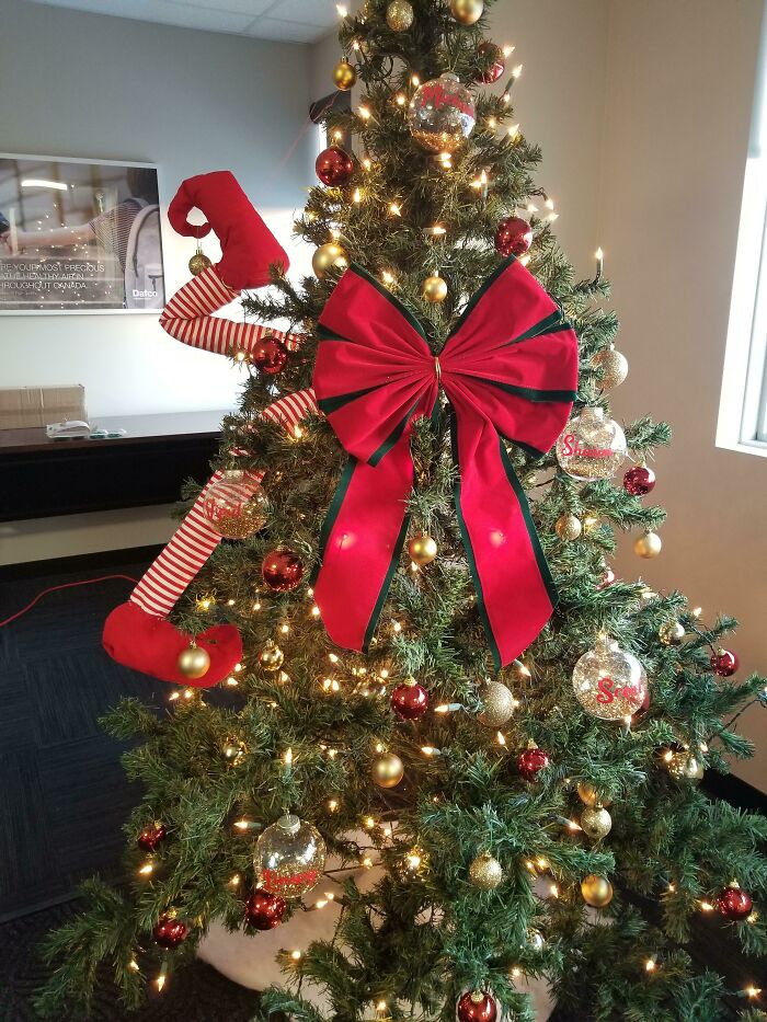 Christmas tree with red bow, candy cane decoration, and gold ornaments, lit with warm white lights.