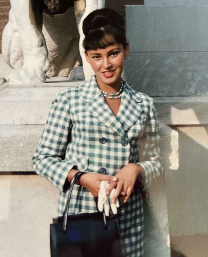 Woman wearing a checkered coat and gloves embodies classic 60s fashion looks.