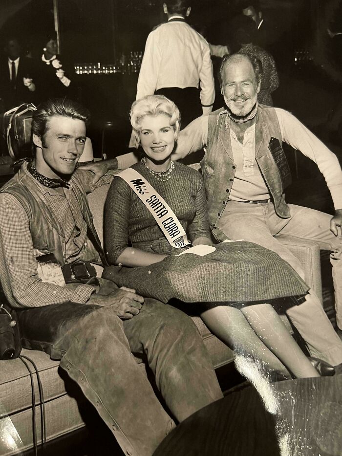 Three people showcasing 60s fashion, sitting together; one wears a "Miss Santa Clara" sash.