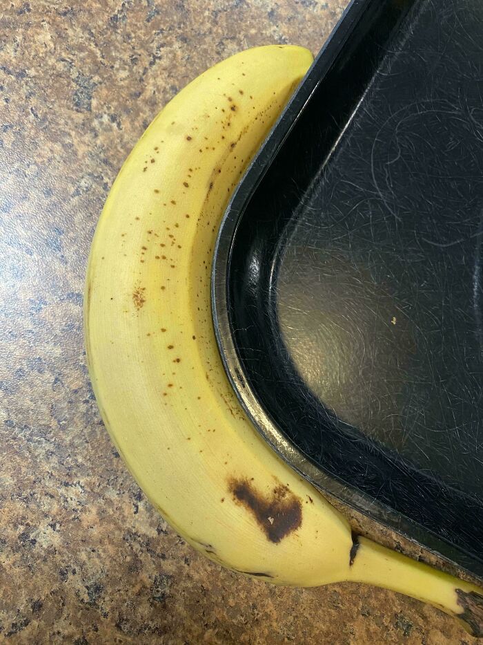 Banana fitting perfectly against a curved black tray, illustrating satisfying perfect fit.