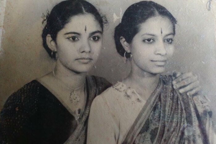 Two women in 60s fashion looks, wearing traditional attire and jewelry, in a vintage black-and-white photograph.
