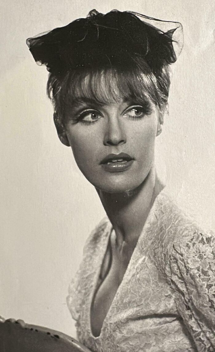 Woman in vintage 60s fashion with lace dress and elegant hat, showcasing classic retro style.