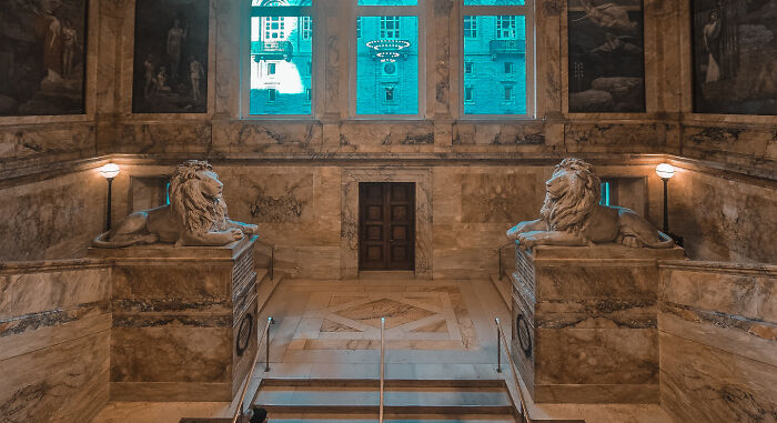 Grand marble interior with detailed lion sculptures and large windows showcasing impressive architectural feats.