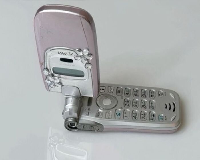 Flip phone with decorative flowers, showcasing old internet feel.
