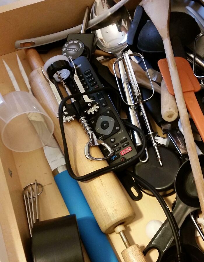 Kitchen drawer filled with various utensils, including a remote control and corkscrew, illustrating funny pregnancy situations.