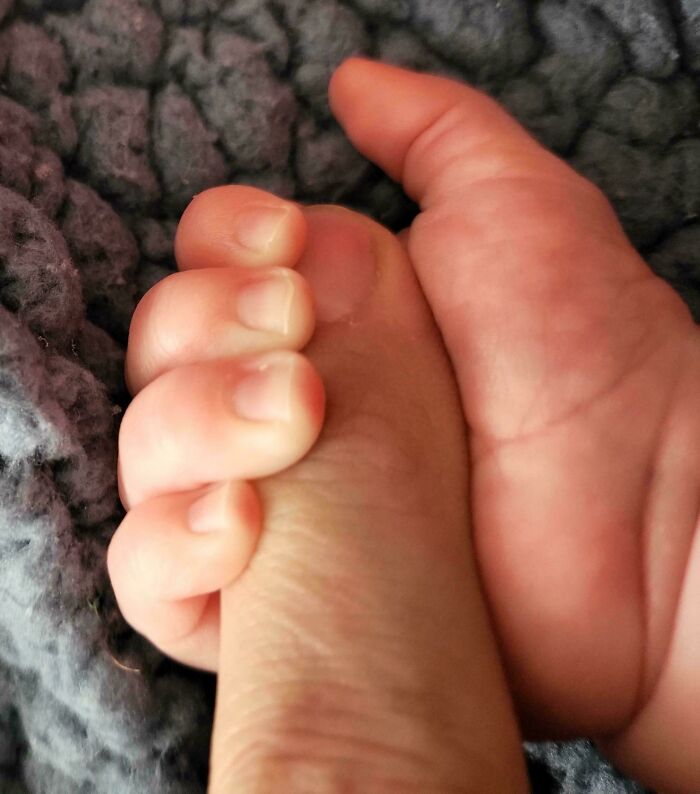 Baby's hand gripping dad's finger, showcasing a tender moment of fatherhood and connection.