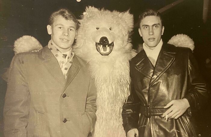 Two men in 60s fashion poses with a person in a bear costume, showcasing vintage styles with coats and scarves.