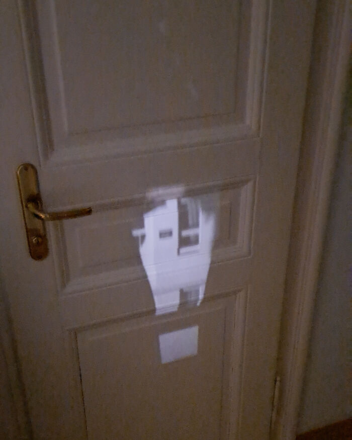 Light reflection creates a fascinating image on a closed wooden door with a brass handle.