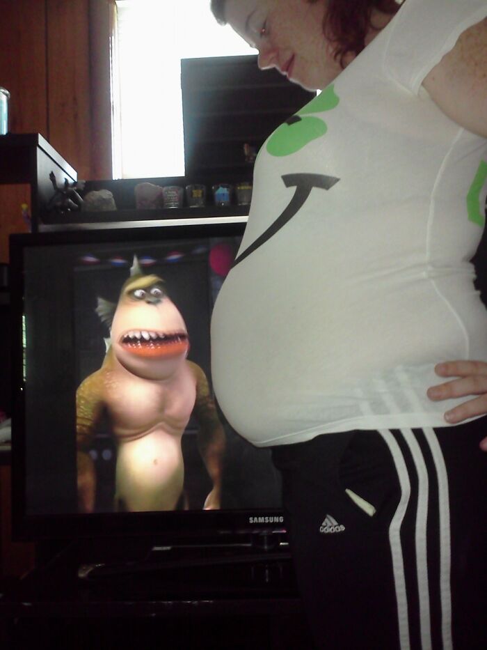 Pregnant woman humorously positioned with cartoon character on TV, creating a funny pregnancy situation.