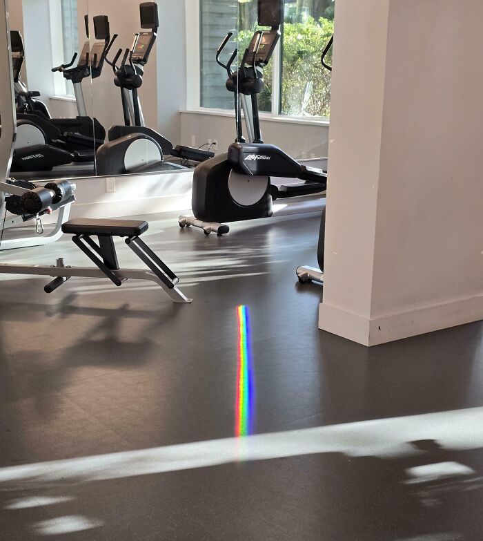 Rainbow reflection on a gym floor, surrounded by exercise equipment, creates a fascinating visual effect.