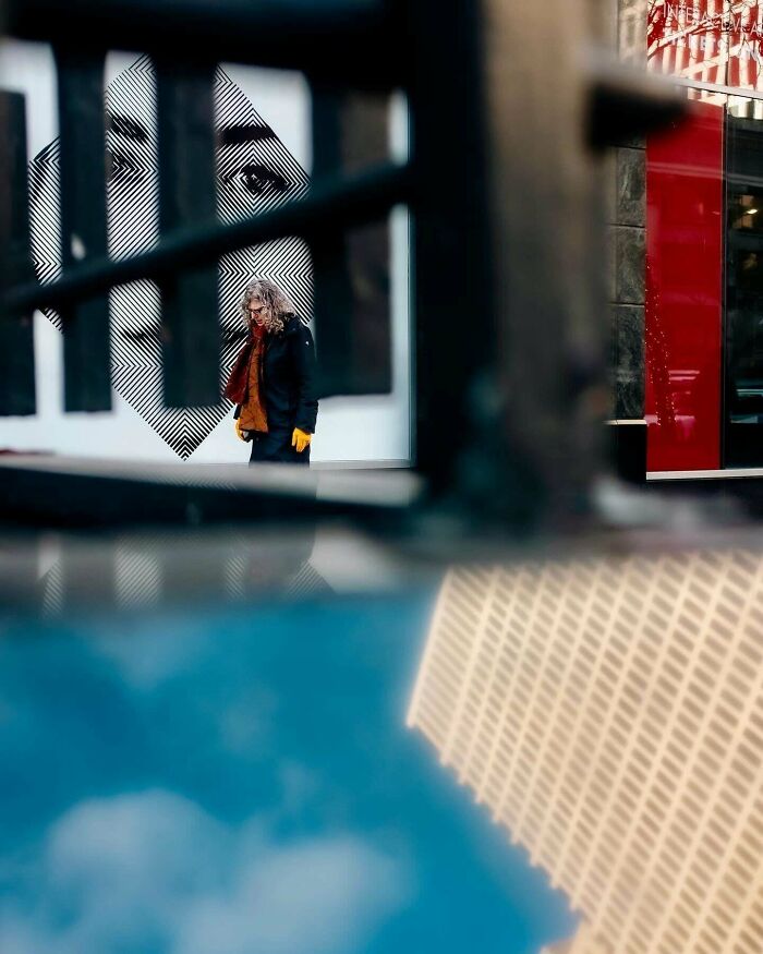 Person with yellow gloves in urban setting, mural background, creative street photography vibe.