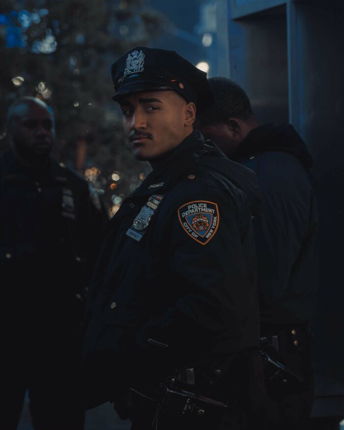 Officer in uniform at night, showcasing Creative-Street-Photography with a city backdrop.