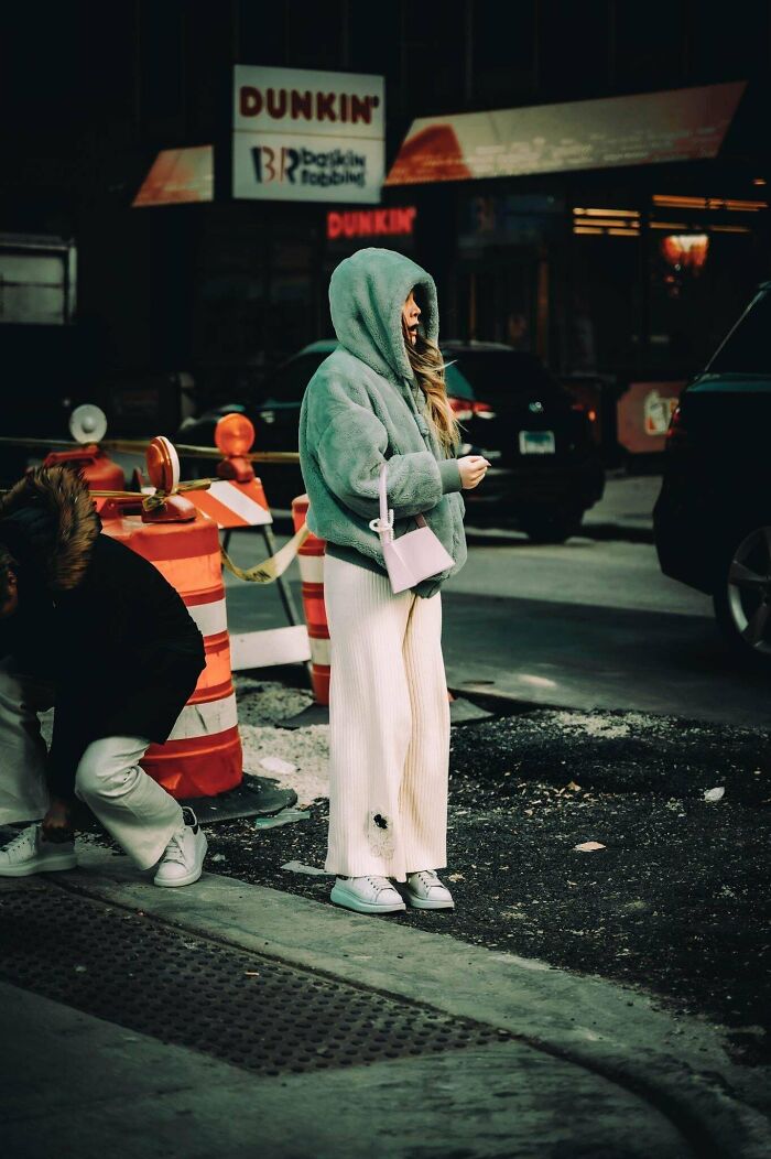 Person in a hoodie stands near construction barriers in a city, exemplifying creative street photography.