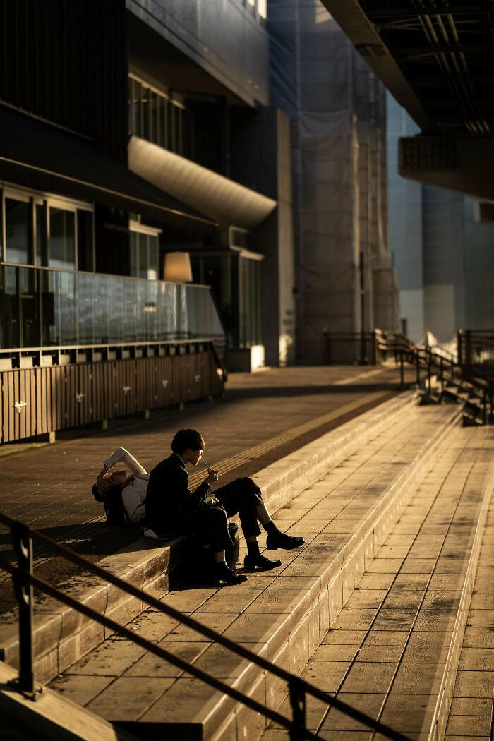People sitting on urban steps in sunlight, capturing a moment of creative street photography.