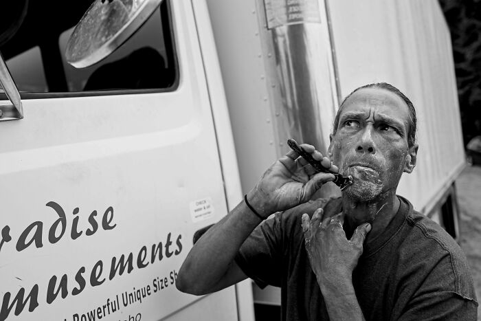 Man shaving in front of a truck in a candid moment, exemplifying creative street photography.
