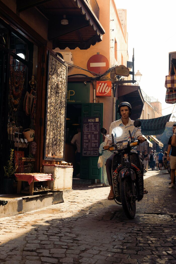 Person on a motorbike in a vibrant street market setting, captured in creative street photography style.