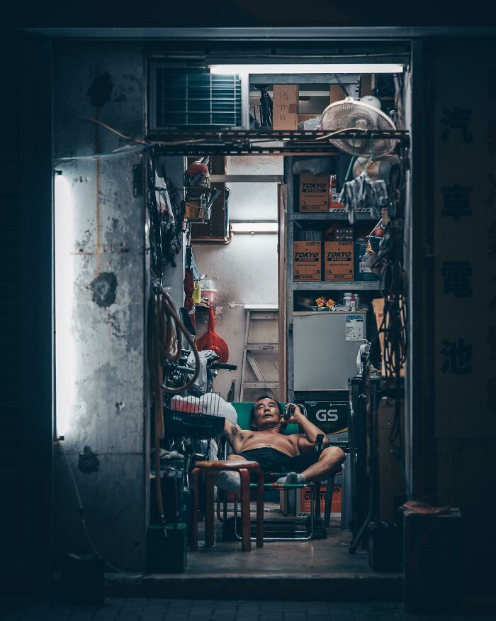 A man reclining in a cluttered workshop, capturing a moment of creative street photography.
