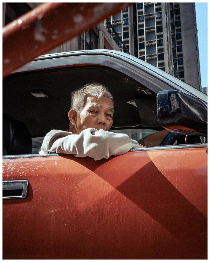 Elderly man in car, captured in a candid moment on a city street, exemplifying creative street photography.