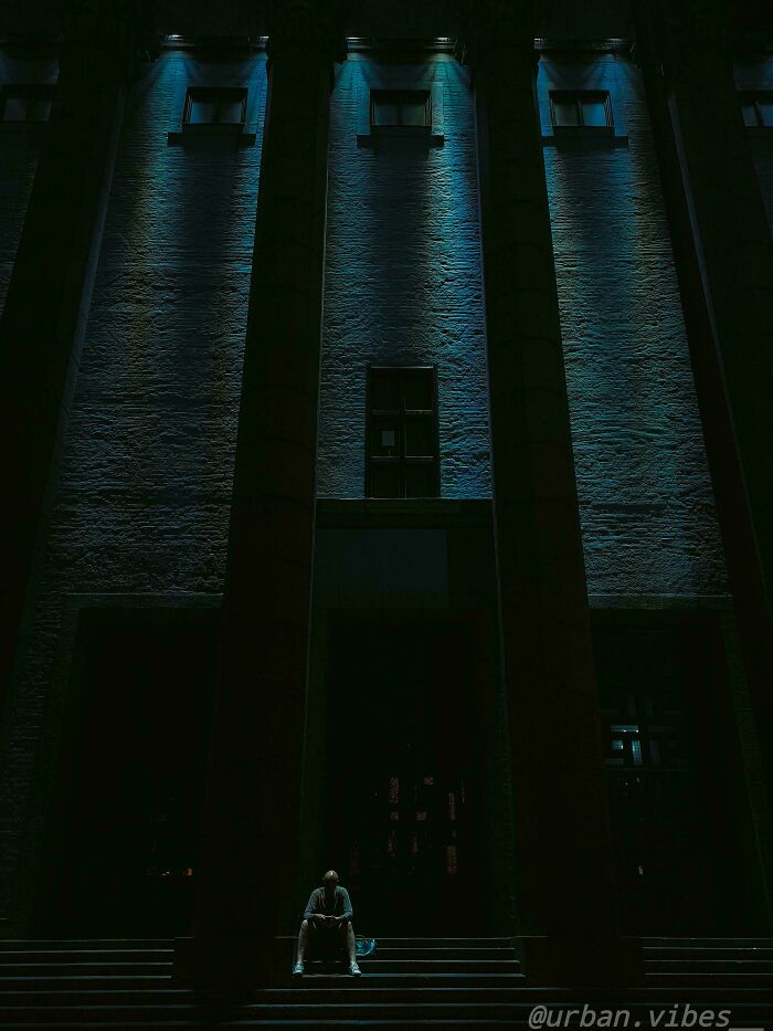 Person sitting on stairs under dramatic lighting in urban environment, exemplifying creative street photography.