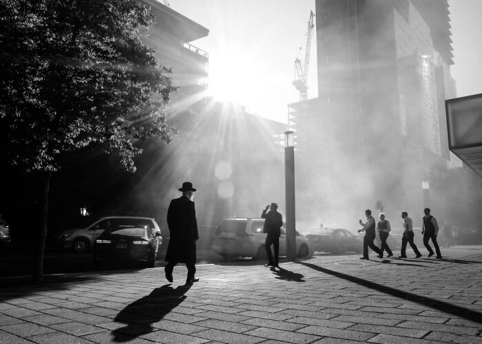 Black and white creative street photography capturing pedestrians in a sunlit city scene.